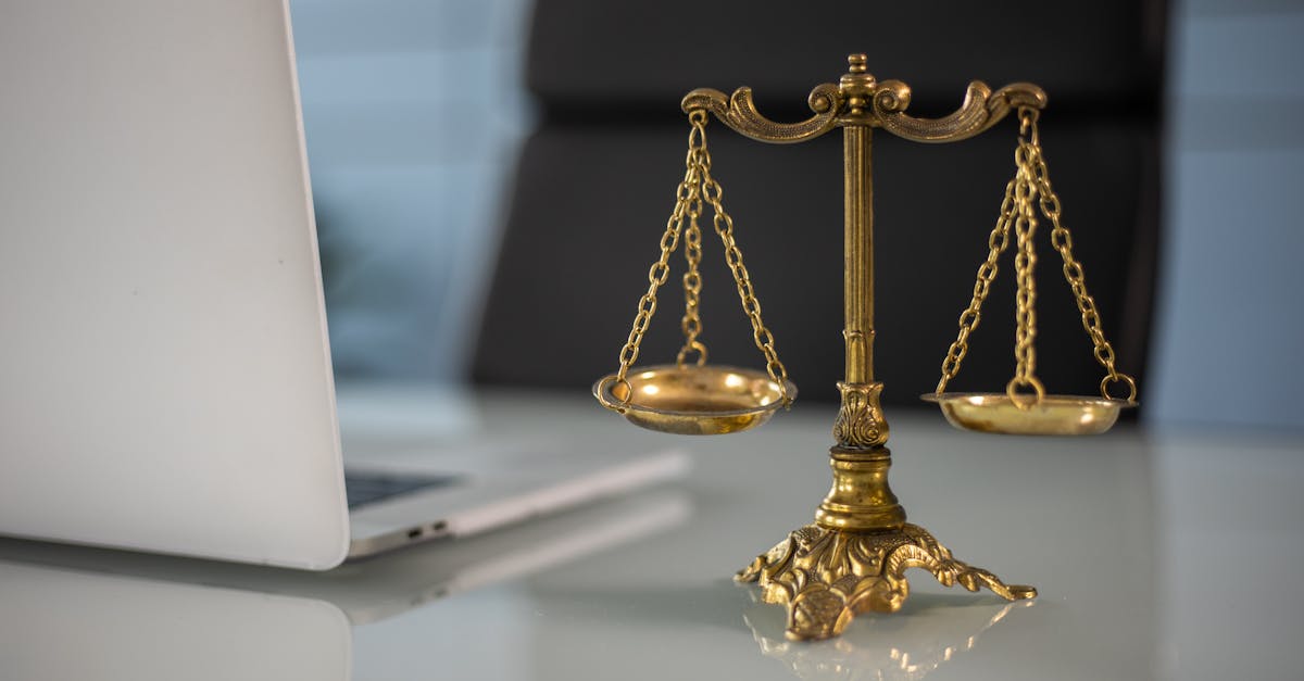Golden justice scales on a desk beside a laptop, symbolizing law and balance.
